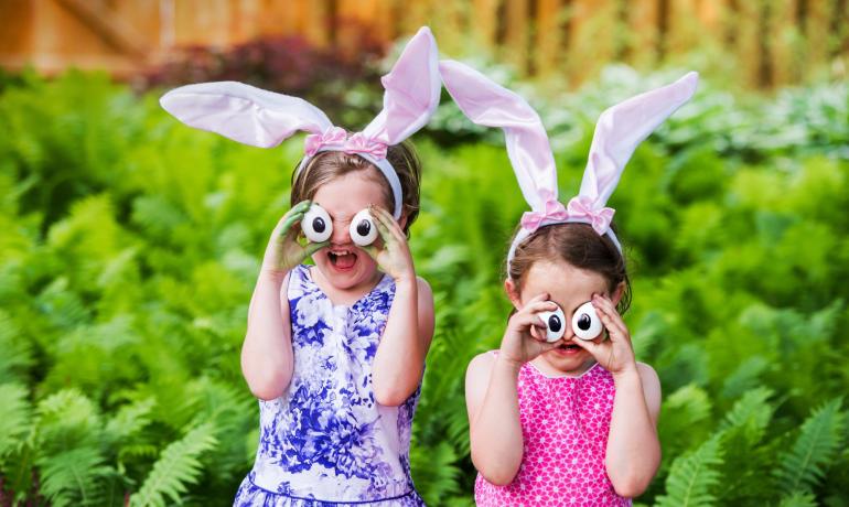 Bambini con orecchie da coniglio e occhi finti in un giardino.