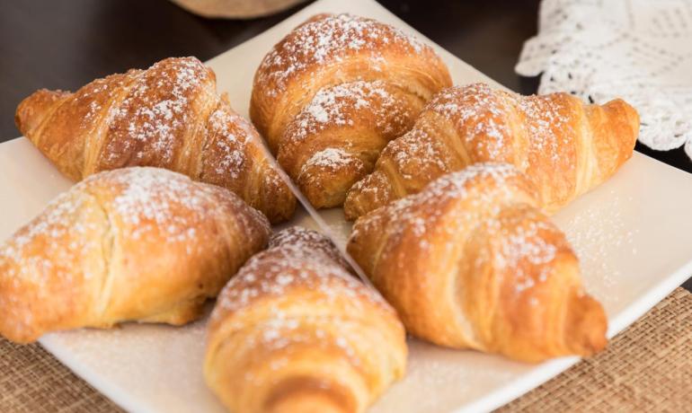 Croissant dolci e al cioccolato su piatti bianchi.