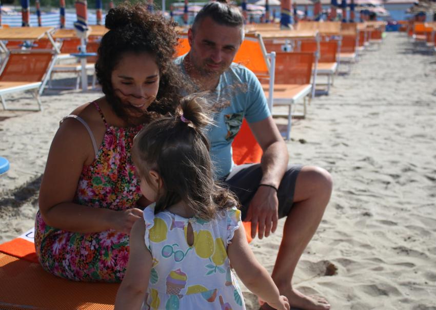 Famille souriante à la plage, soleil et joie estivale.